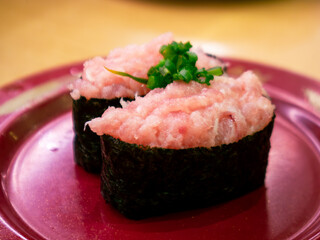 Negitoro minced fatty tuna gunkan maki sushi topped with green onion on red plate, Japanese restaurant © Tavan
