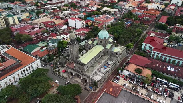 Aerial oblique view reveals Manila Cathedral with prominent dome and bell tower rising above dense Intramuros district surrounded by colonial-era buildings with terracotta rooftops and narrow streets