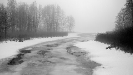 Obraz premium foggy spring landscape with a frozen river, blurred tree outlines in the background, damp and cloudy spring,