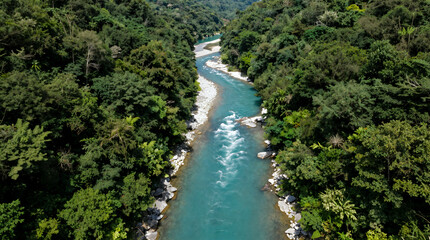 Fototapeta premium Aerial Drone View of a Winding Turquoise River Flowing Through Lush Green Tropical Rainforest with White Water Rapids and Rocky Banks