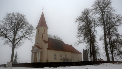 spring landscape with a small rural church in the morning mist, damp foggy and cloudy weather