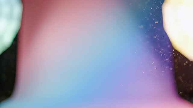 Abstract image with a vibrant color gradient of pink, blue, and purple, speckled with light
