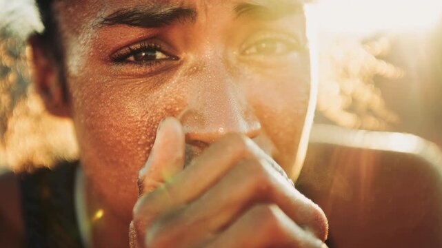 Close up of a sweating African American female athlete with hands clasped in bright sunlight. This intense sports emotion scene shows a tired runner hoping or resting after a hard workout