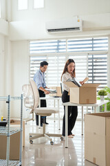 Obraz premium Young business officer creative start up business or Young colleagues moving and unpacking cardboard boxes in office. company relocation.