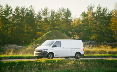 Fototapeta premium White vehicle on road beside green field