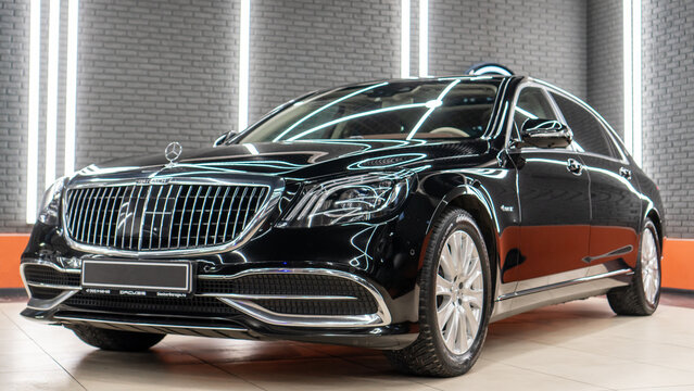 Black Mercedes-Maybach S-Class luxury sedan front view showcasing glossy paint and vertical chrome grille inside a professional detailing studio.