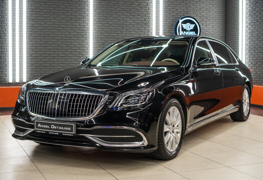 Black Mercedes-Maybach S-Class luxury sedan front view showcasing glossy paint and vertical chrome grille inside a professional detailing studio.