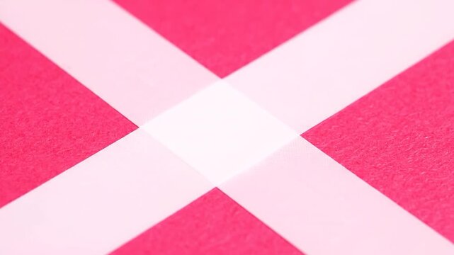 Close-up of pink textured surface intersected by two light-colored strips, forming an X