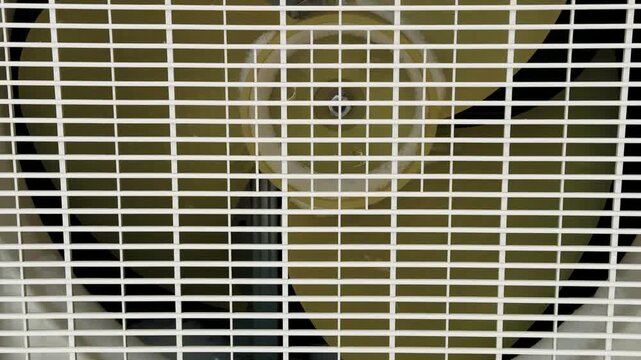 Closeup Air Conditioner Fan Grille Showing Rotating Blades During Maintenance Inspection, Dust Accumulation On Plastic Housing, Exposed Motor And Wiring, Shadowed Background, High detail.