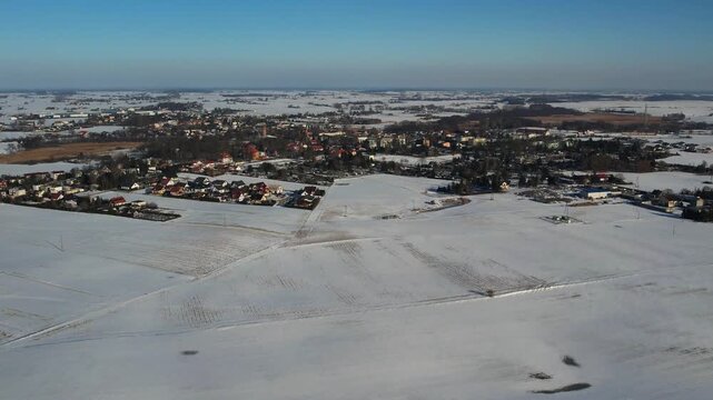 Winter aerial of rural town and snowy fields under blue sky, contryside landscape 4k.