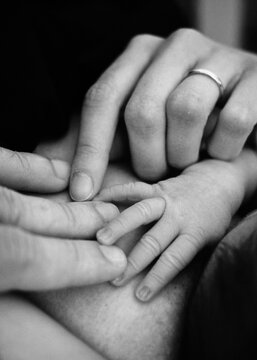 Foto scattata alle mani di una neonata e dei suoi genitori.
