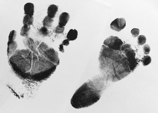 Foto scattata a delle impronte di un piede e di una mano di un bambino neonato.