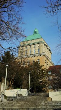 Vertical panning shot of the University of Zurich (UZH) main building in Switzerland, showing the grand stone staircase leading up to the historic tower with its green domed roof.
