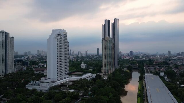 Jakarta, Indonesia: Aerial drone footage of modern skyscraper, luxury hotel and condominium towers along the Ciliwung river at sunset in the Jakarta business district in Indonesia capital city. 