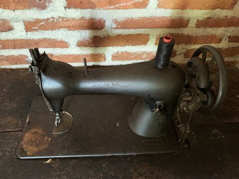 Antique vintage sewing machine on rustic wooden table against brick wall. old sewing machine.