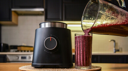 Pouring a vibrant purple berry smoothie from a blender into a tall glass © shine.graphics