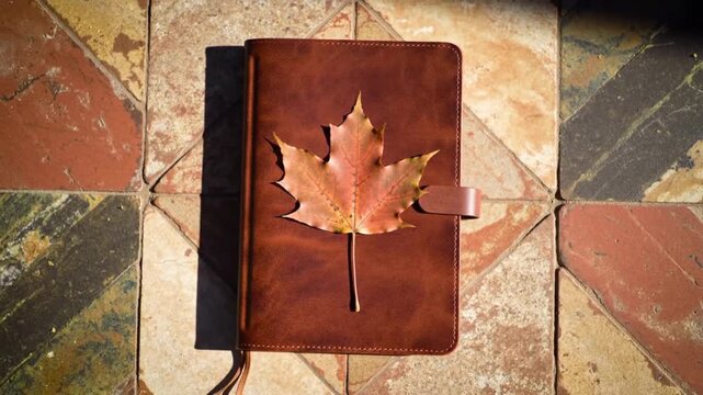 Journal with maple leaf decoration rests on weathered tile background.