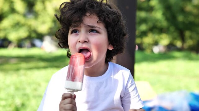Armenian boy enjoying popsicle in park on a summer day, childhood sweetness