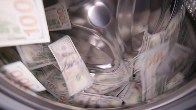 United States Dollar banknotes flying around inside a washing machine drum - closeup wide angle view for money laundering and fraud concept.