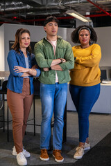 Diverse coworkers standing with arms crossed in open-plan office near desks and monitors