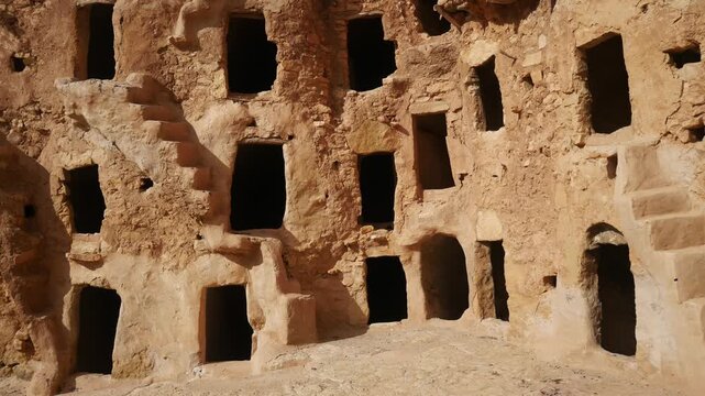 Panorama: Ancient Ksar Mrabtine in southern Tunisia, featuring traditional Berber mudbrick granaries and arched storage rooms, showcasing Saharan architecture, history, and cultural heritage