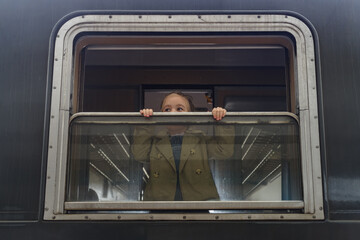 Smiling little girl looking from a window of old tourist train