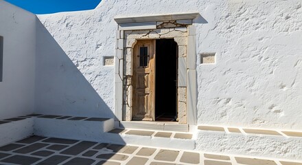 Ornate Wooden Door Open on Whitewashed Building with Sunlight and Shadows