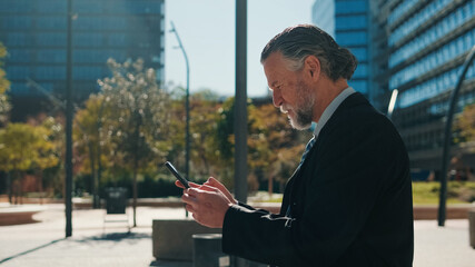 Fototapeta premium Professional Older Man Using Smartphone in City Park