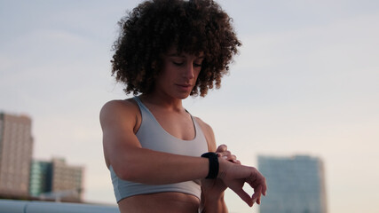 Curious Woman Checks Fitness Watch Outdoors at Sunset