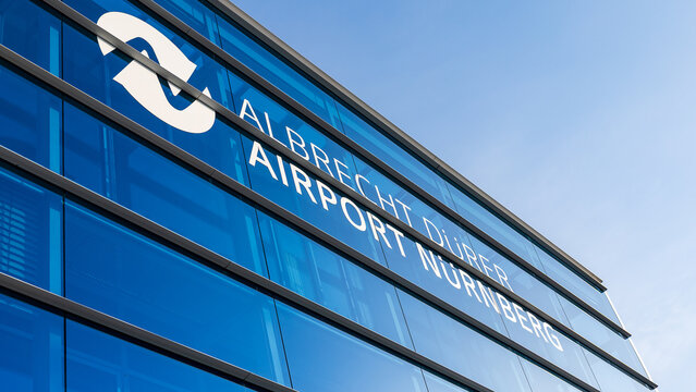 Detailansicht der Glasfassade des Terminals mit dem Schriftzug &bdquo;Albrecht D&uuml;rer Airport N&uuml;rnberg&ldquo; und Logo. 