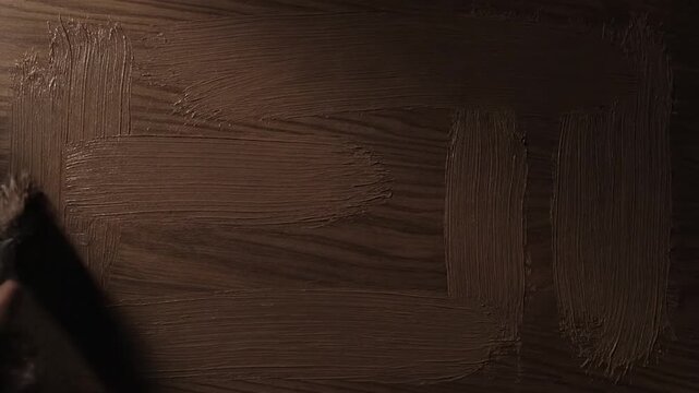 Textured, dark brown strokes of paint on a wood grain background create a rectangular frame