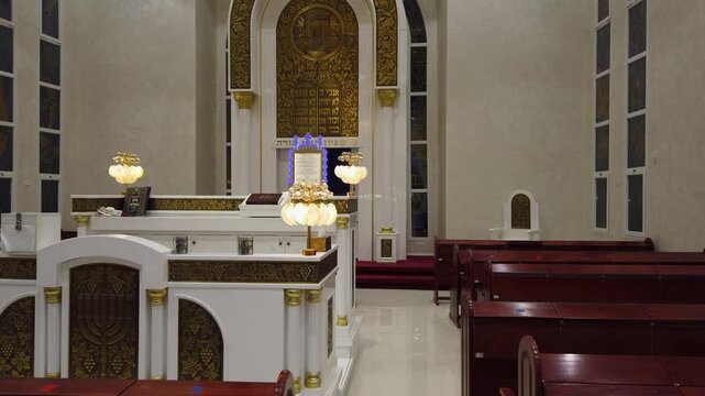Interior view of a modern synagogue with a golden Holy Ark, ornate chandelier and wooden benches, Israel