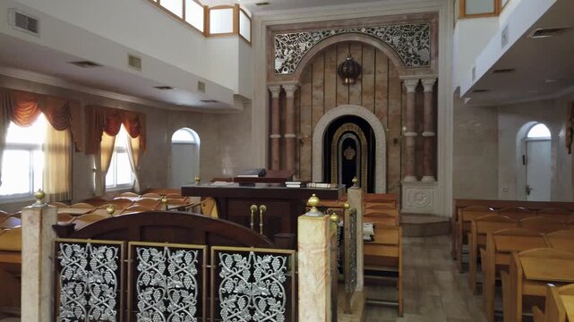 Interior view of a modern synagogue with a golden Holy Ark, ornate chandelier and wooden benches, Israel