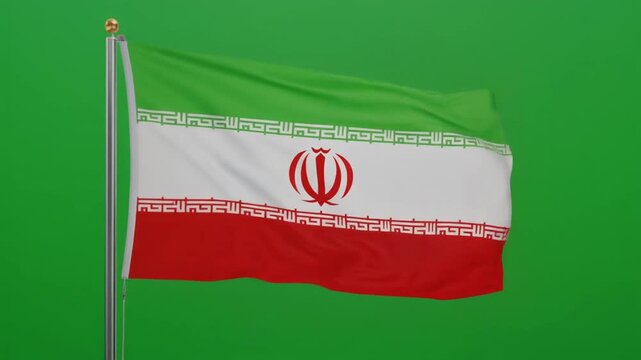 The national flag of Iran with green, white, and red horizontal bands, central emblem, and Kufic script borders, mounted on a flagpole against a green background.