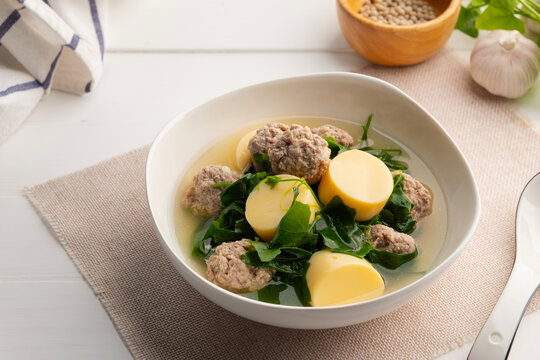 Vegetable gourd soup with minced pork and tofu in white bowl on wooden table,Thai food.(gaeng jued tum luang)