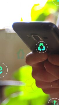 Vertical video: Woman holding phone and tilting near window, eco icons moving as checking eco data