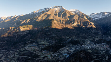 Small mountain town nestled in a valley surrounded by snowy peaks and green fields