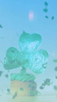 Vertical video: Soft burst sending shamrocks down around cupcake, dusting mint frosting for joy