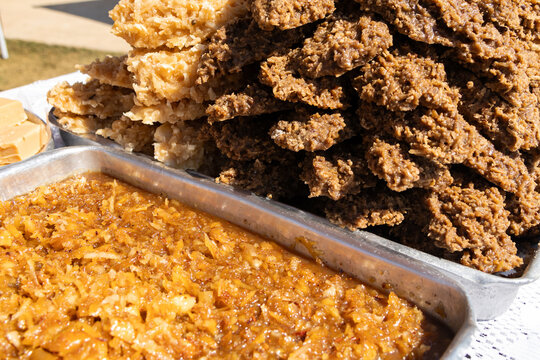 A close-up of assorted traditional Brazilian cocada sweets in metal trays. 