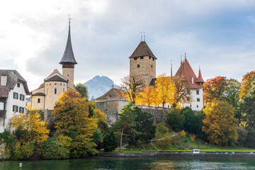Obraz premium View of Schloss Spiez castle and autumn trees from the lake. Spiez, Canton of Bern, Switzerland.