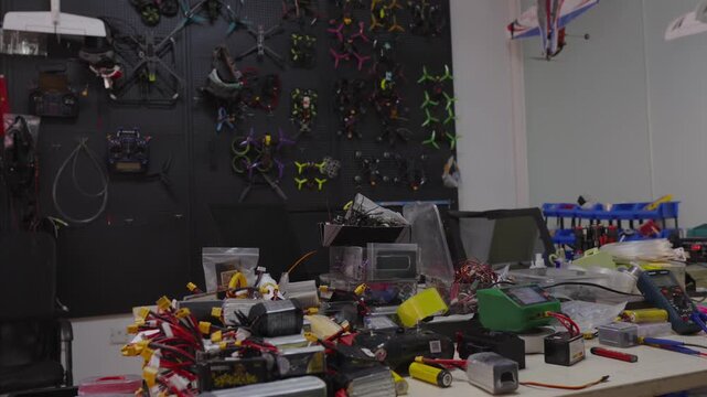 Workbench displaying a scattered arrangement of electronic components, wires, tools, and hardware, creating busy and authentic workspace environment for development or repair