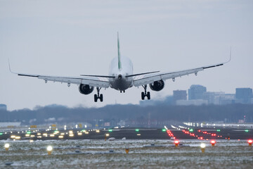 Aircraft approaching the landing strip with runway lights glowing in the evening dusk