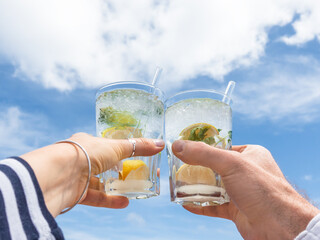 A man’s and woman’s hands hold glasses with drinks. Cruise ship deck. Against the backdrop of sea waves. Vacation and travel concept. Chill lifestyle, luxury travel. Holiday and travel themes © Svetlana