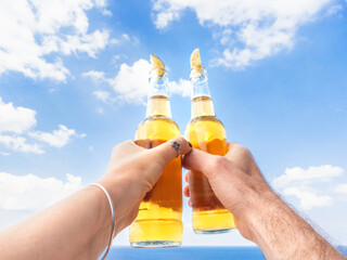 Men's and women's hands and two bottles of beer. Cruise ship deck. Against the backdrop of sea waves. Vacation and travel concept. Chill lifestyle, luxury travel. Perfect for holiday and travel themes © Svetlana