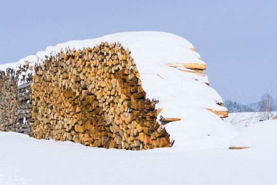 Brennholzstapel als Heizmaterial-Vorrat im Schnee