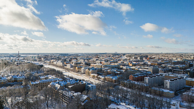 Aerial winter panorama of Turku city and the frozen Aurajoki river under deep snow, Finland.