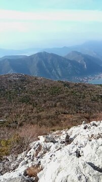 High altitude hiking viewpoint above Dobrota revealing limestone cliffs, layered mountains and deep blue Bay of Kotor. Symbolizes adventure travel cinematics and active Mediterranean exploration theme
