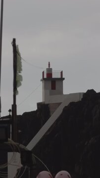Vertical view of a small lighthouse beacon on volcanic cliffs, C&acirc;mara de Lobos, Madeira