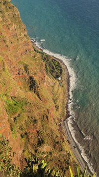 Vertical POV of turquoise ocean waves hitting the shore beneath Cabo Gir&atilde;o, Apple Log 2