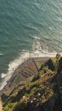 Vertical 4K bird's-eye view from Cabo Gir&atilde;o cliff overlooking Atlantic terraces, Madeira